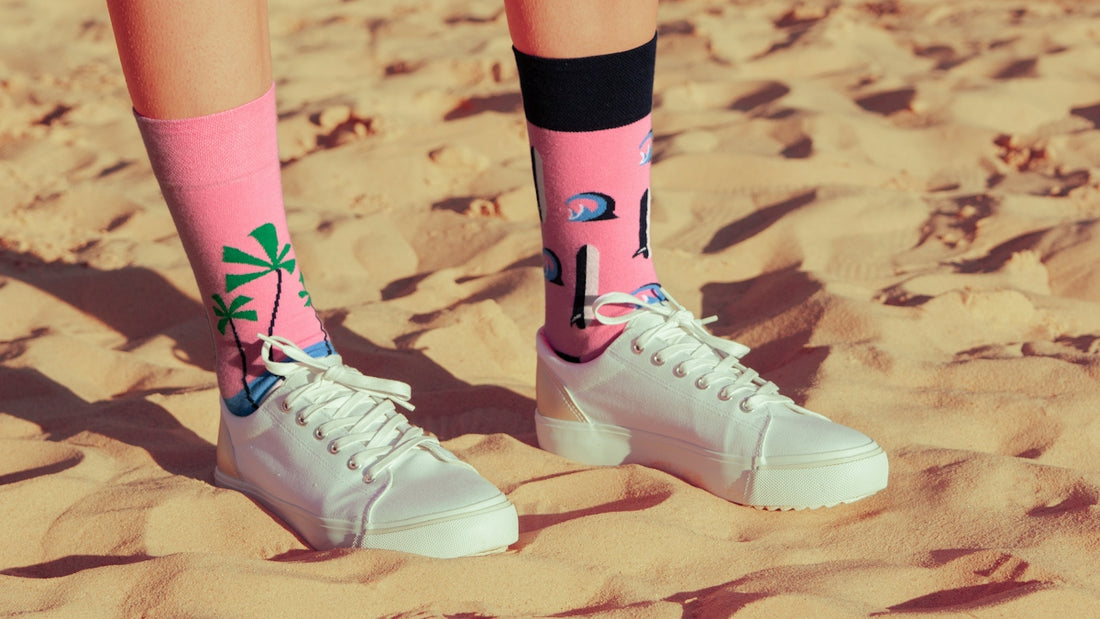 a person standing in the sand wearing white tennis shoes