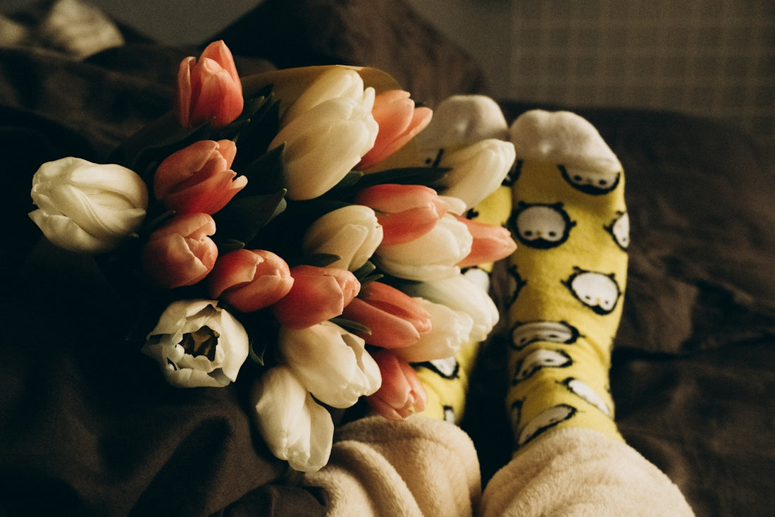 a bouquet of tulips and tulip socks on a bed