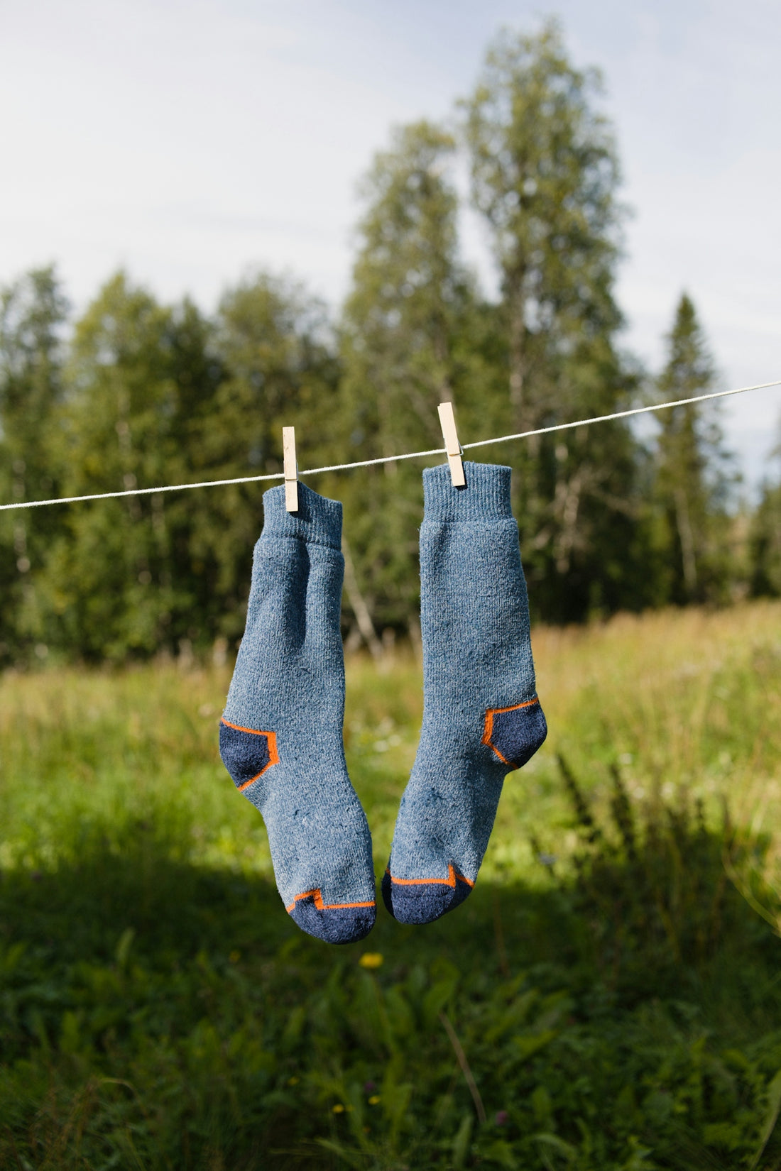 A pair of blue socks hanging from a clothes line