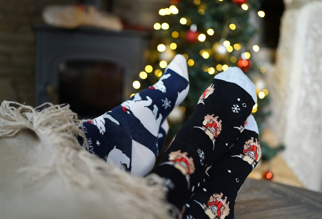 A person's feet with christmas socks on in front of a christmas tree