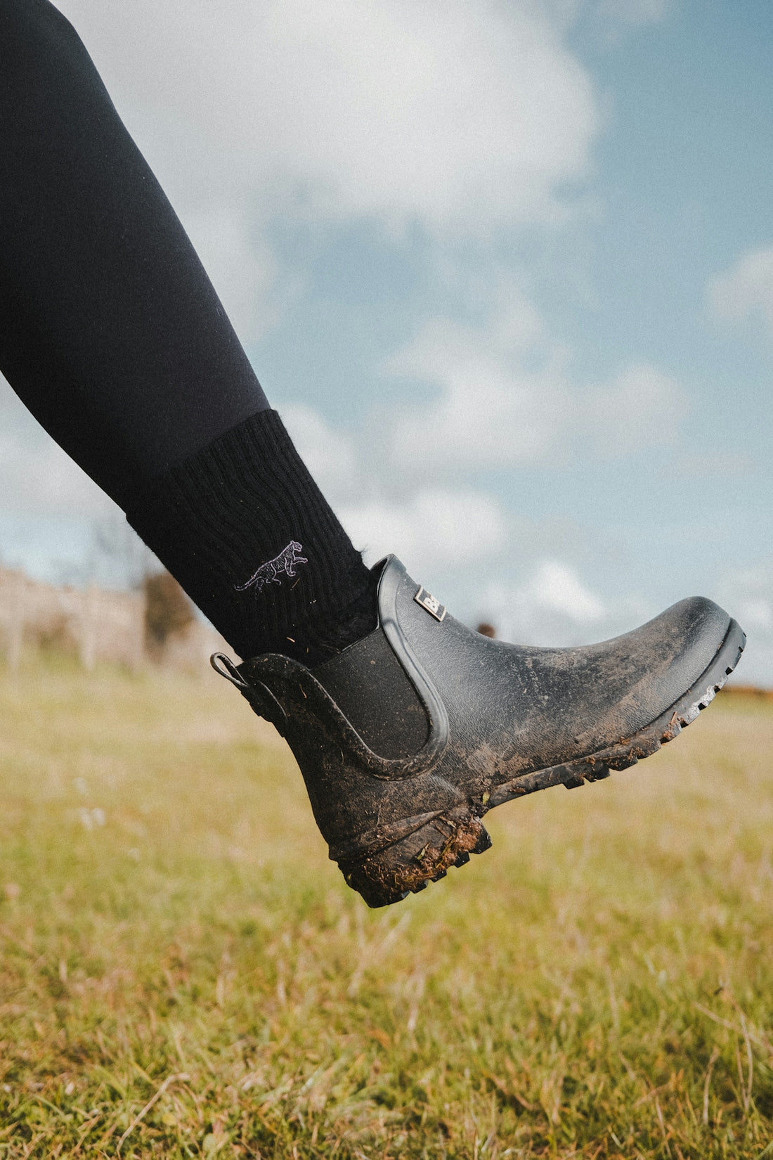 A person standing in a field wearing black boots