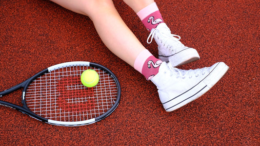 A woman sitting on the ground with a tennis racket and ball