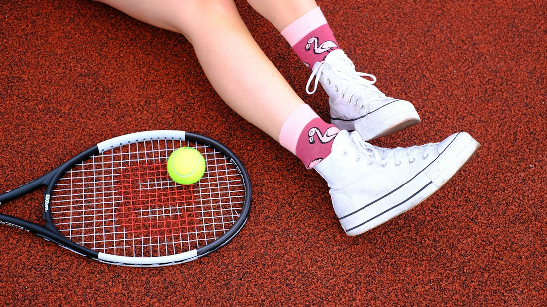 A woman sitting on the ground with a tennis racket and ball