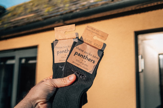A person holding up a pair of black socks