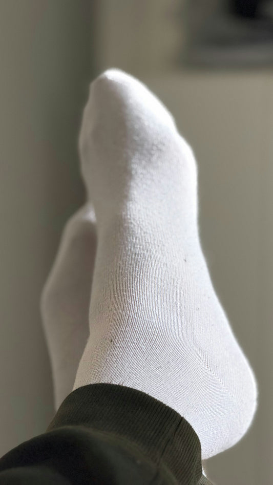 A pair of white socks on feet.
