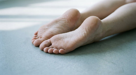Close-up of bare feet on a cool concrete surface with subtle moisture droplets on the skin, lit by soft natural light.