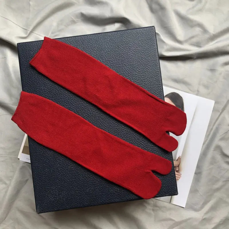 Red cotton toe socks laid on a black textured box, perfect for comfort and style.