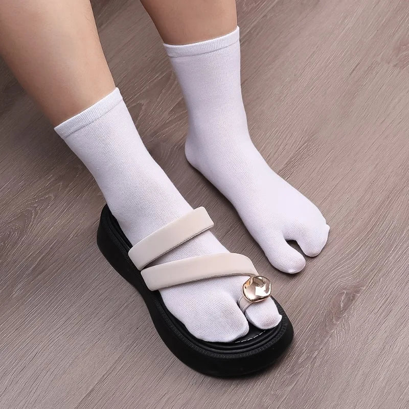 Stylish black sandals with white toe socks, featuring double straps and a decorative buckle.
