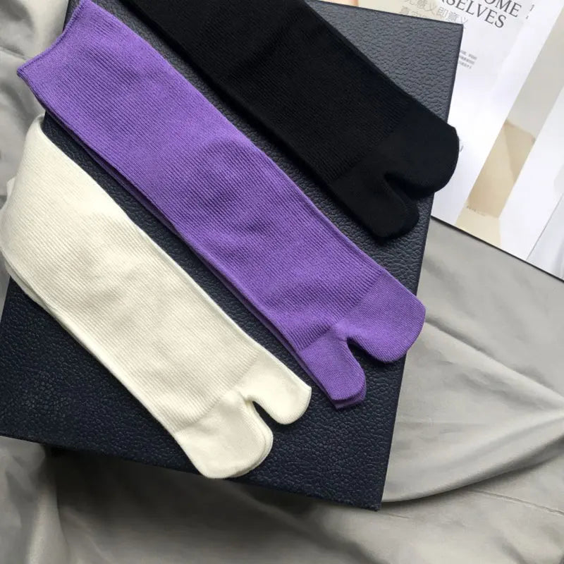 Three pairs of stylish toe socks in black, purple, and white, made from soft, breathable material.